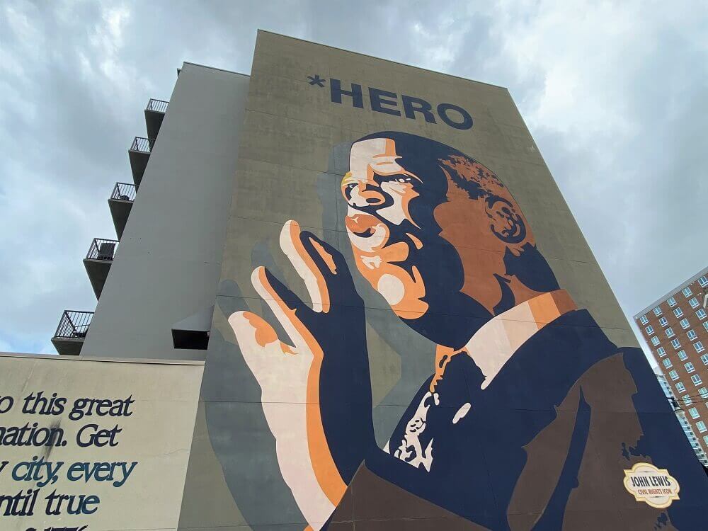 An enormous mural of John Lewis labeled Hero covers the side of a multi-story building