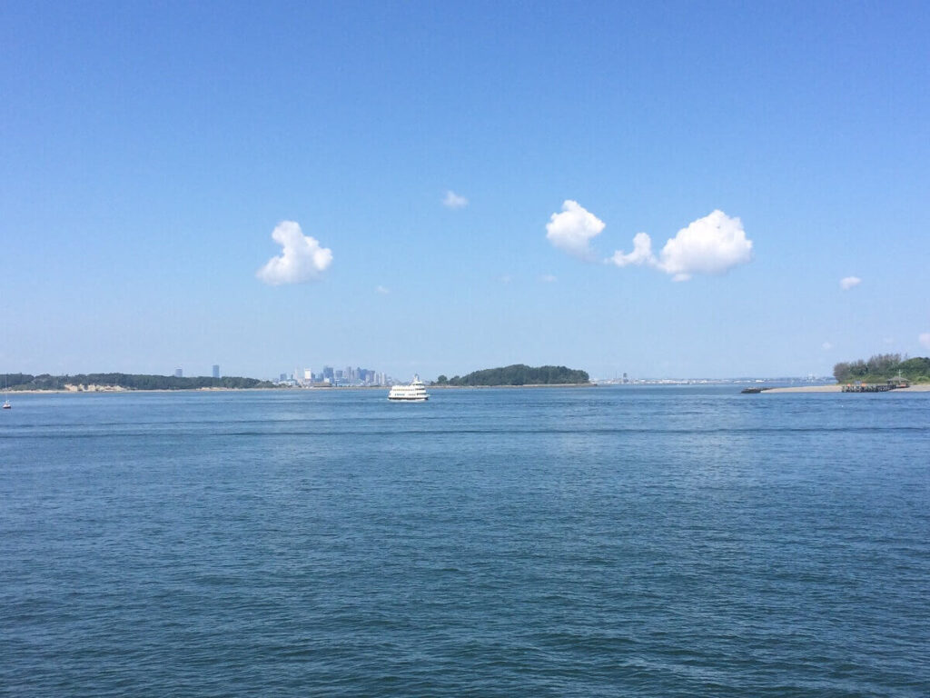 View of Boston Harbor, including some islands, a ferry, and the city skyline in the background
