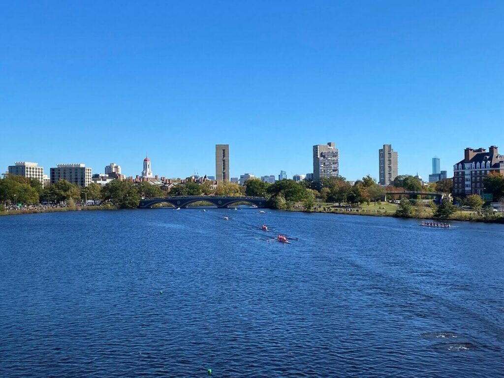 View from above of boats racing on the river with Boston skyline behind