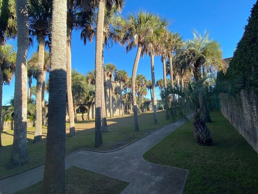 Palm trees grow in a sunny courtyard with the Atalaya tower in the background