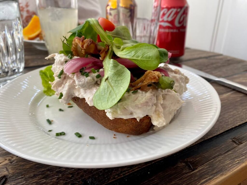 Greens, bacon and chicken salad sit on top of a slice of bread