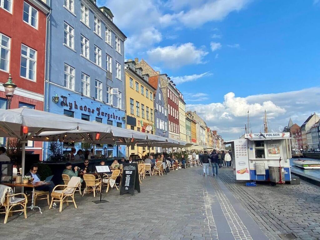 People eat at restaurants along a street full of colorful buildings