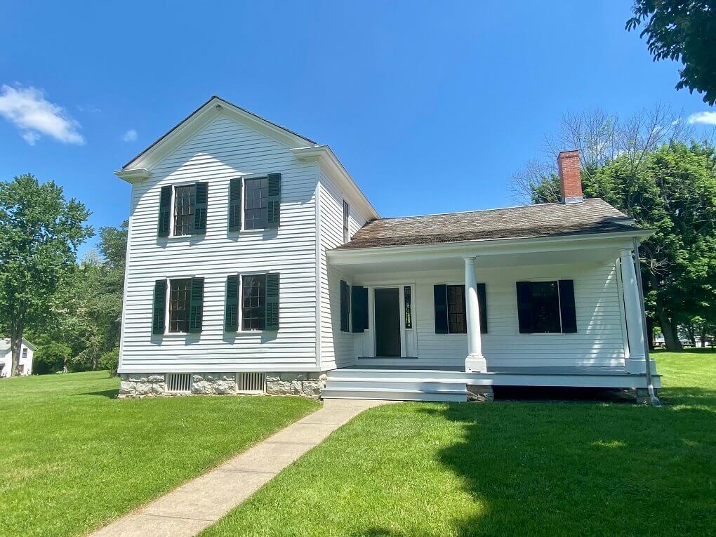 An old white house with a porch and a second story on one half
