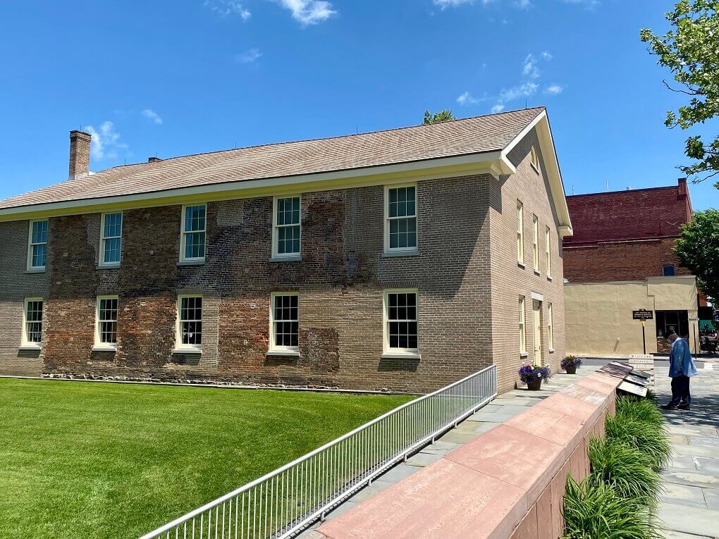 An old brick building stands next to a green lawn